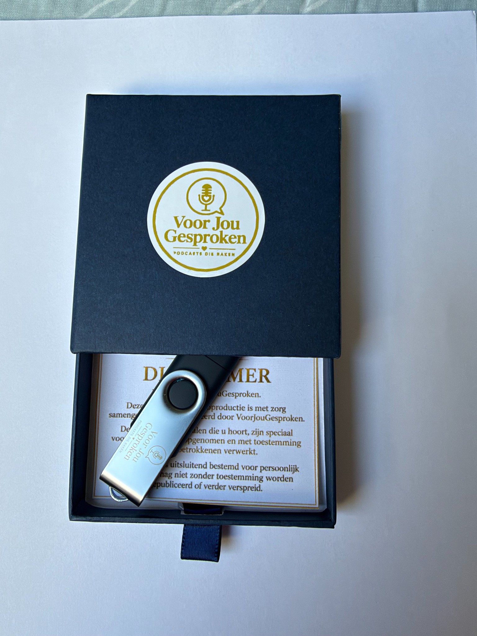 Geopende geschenkdoos met USB-stick en disclaimerkaart